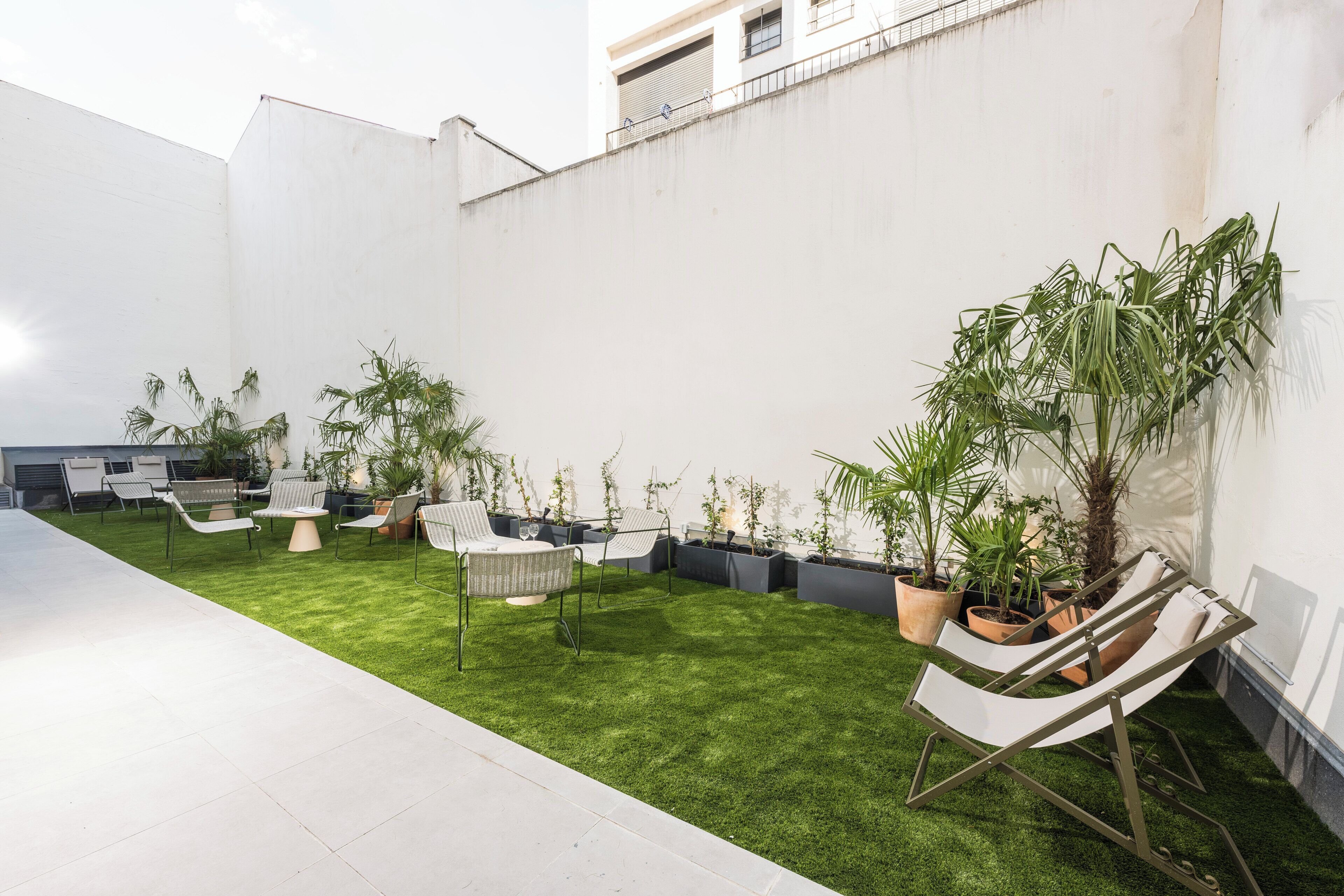 A rooftop garden with artificial grass, outdoor seating, and potted plants.