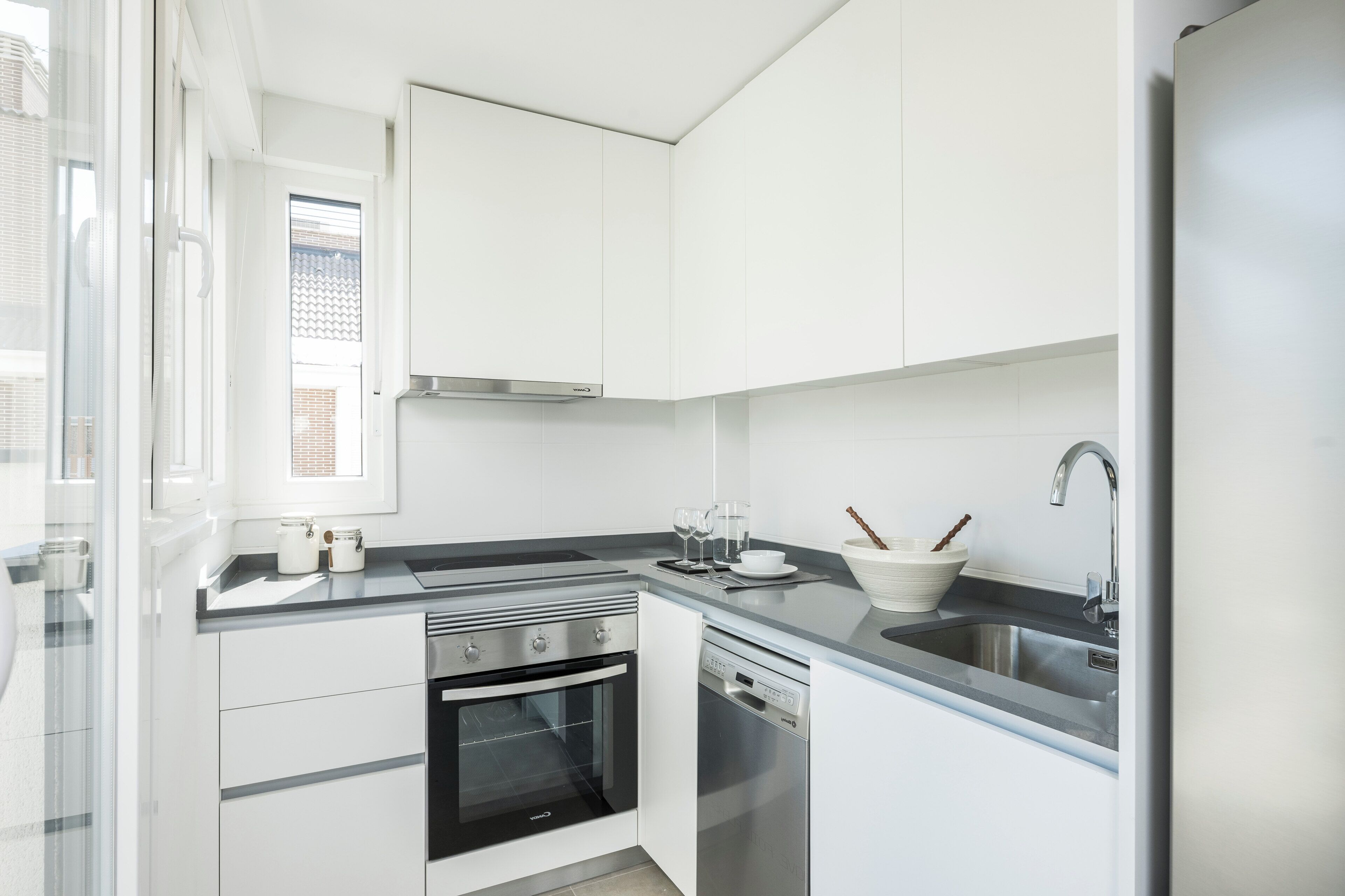 A modern kitchen with white cabinetry, a stainless steel range, an oven, a dishwasher, and a sink.