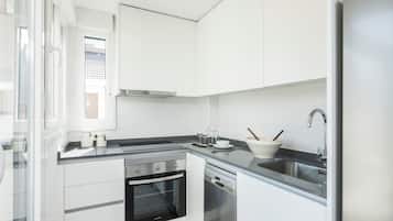 Een moderne keuken met witte kasten, een roestvrijstalen fornuis, een oven, een vaatwasser en een spoelbak.