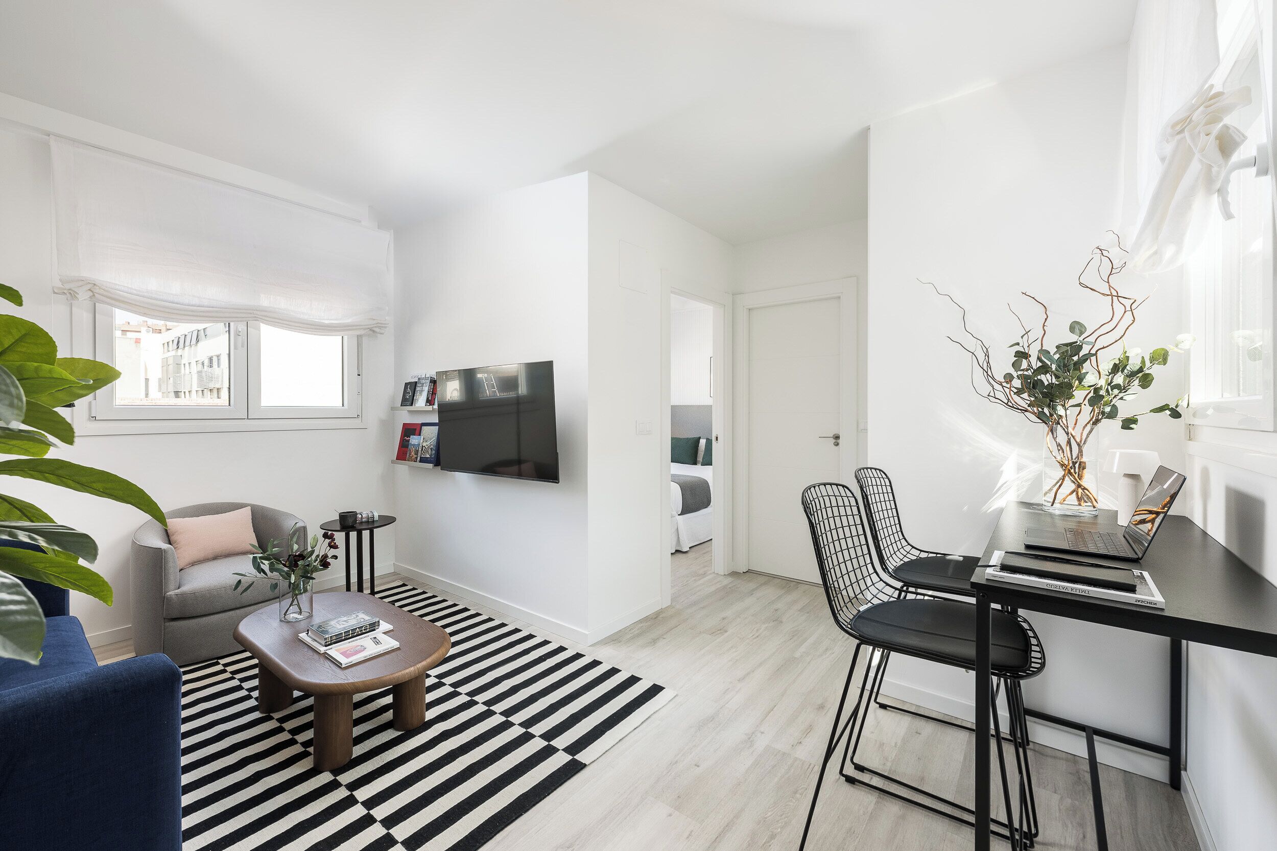 Een moderne woonkamer met een bank, salontafel en een aan de muur bevestigde televisie.