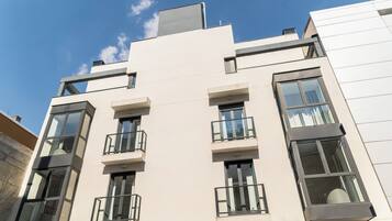 Un edificio moderno de varios pisos con balcones, ventanas grandes y techo plano.