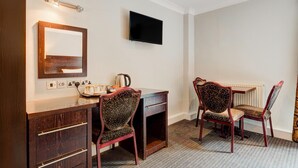 A hotel room with a wooden desk, two upholstered chairs, a flat-screen TV, and a mirror on the wall. - Standard family of 5 room (Liverpool)