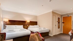 A hotel room with two beds, a wooden headboard, a carpeted floor, and a door with a mirror. - Standard family of 5 room (Liverpool)