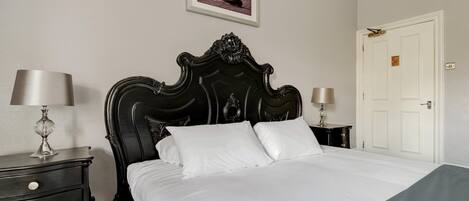 A neatly made bed with white linens in a room with a classic black headboard.