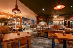 A restaurant interior with wooden tables and chairs, hanging light fixtures, and a bar area. - Manchester Portland By Sunday - Standard Single Room (Manchester)