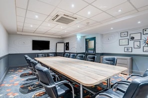 A conference room with a long table, chairs, a flat-screen TV, a whiteboard, and a clock on the wall. - Manchester Portland By Sunday - Standard Single Room (Manchester)