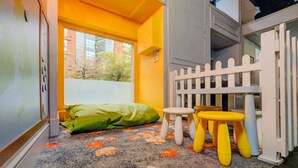 A child's play area with a white picket fence, a green cushion, and two small stools.