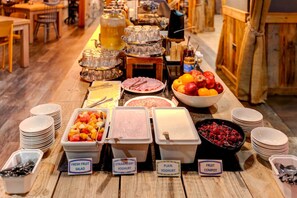 A buffet table with various food options including fresh fruit salad, strawberry yogurt, plain yogurt, and fruit compote.