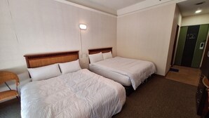 Camera d'albergo con due letti, una testiera in legno, una lampada a parete e pavimento con moquette.