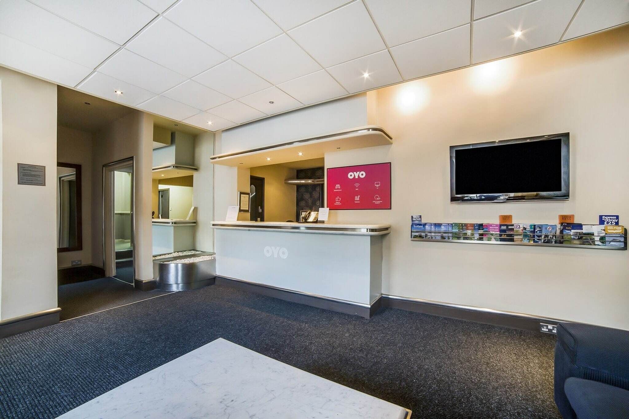 A reception area with a counter, a television mounted on the wall, and a display of products on the wall.
