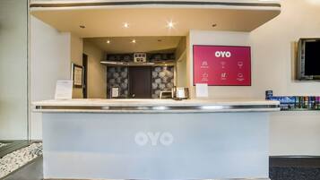 A reception desk with the OYO logo, a digital display, and a framed certificate on the wall.
