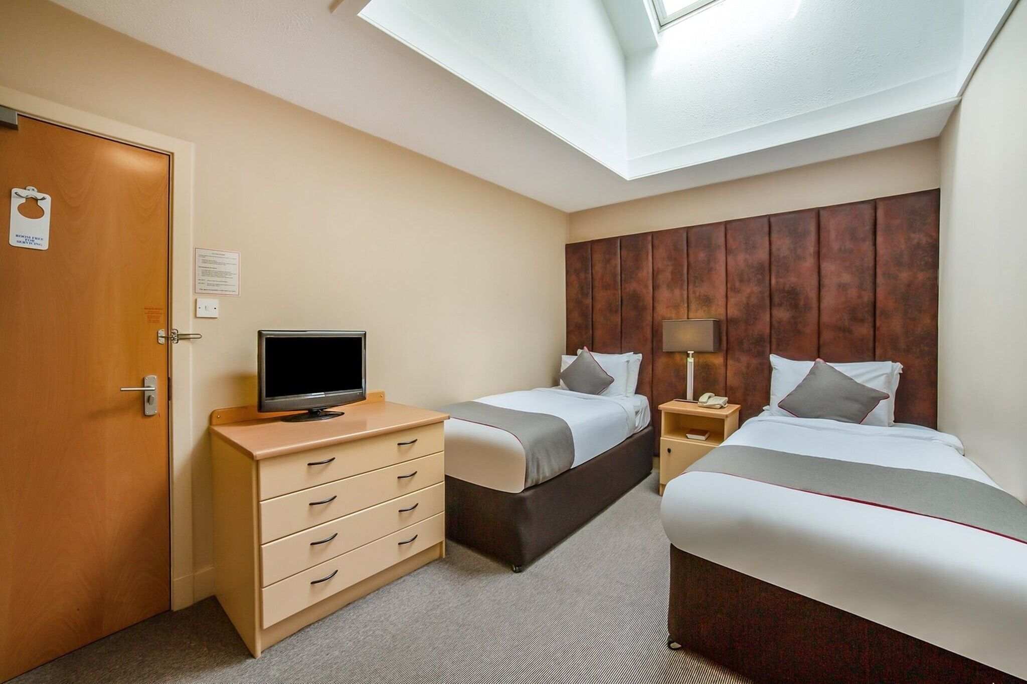 A hotel room with two beds, a TV, a desk, and a wardrobe.