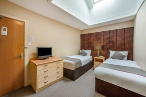 Quarto de hotel com duas camas, televisão, escrivaninha e guarda-roupa.