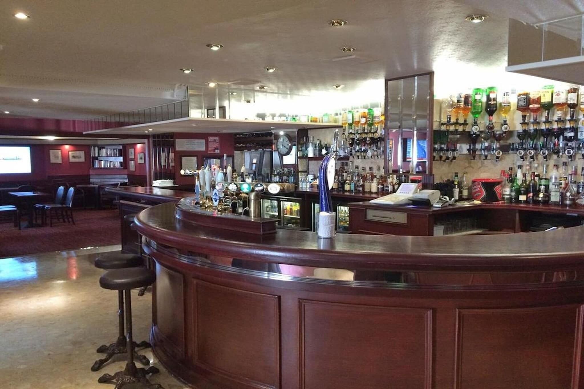 A bar area with a counter, stools, and a wall of liquor bottles.