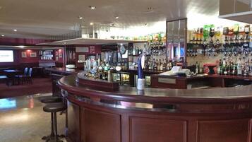 A bar area with a counter, stools, and a wall of liquor bottles.