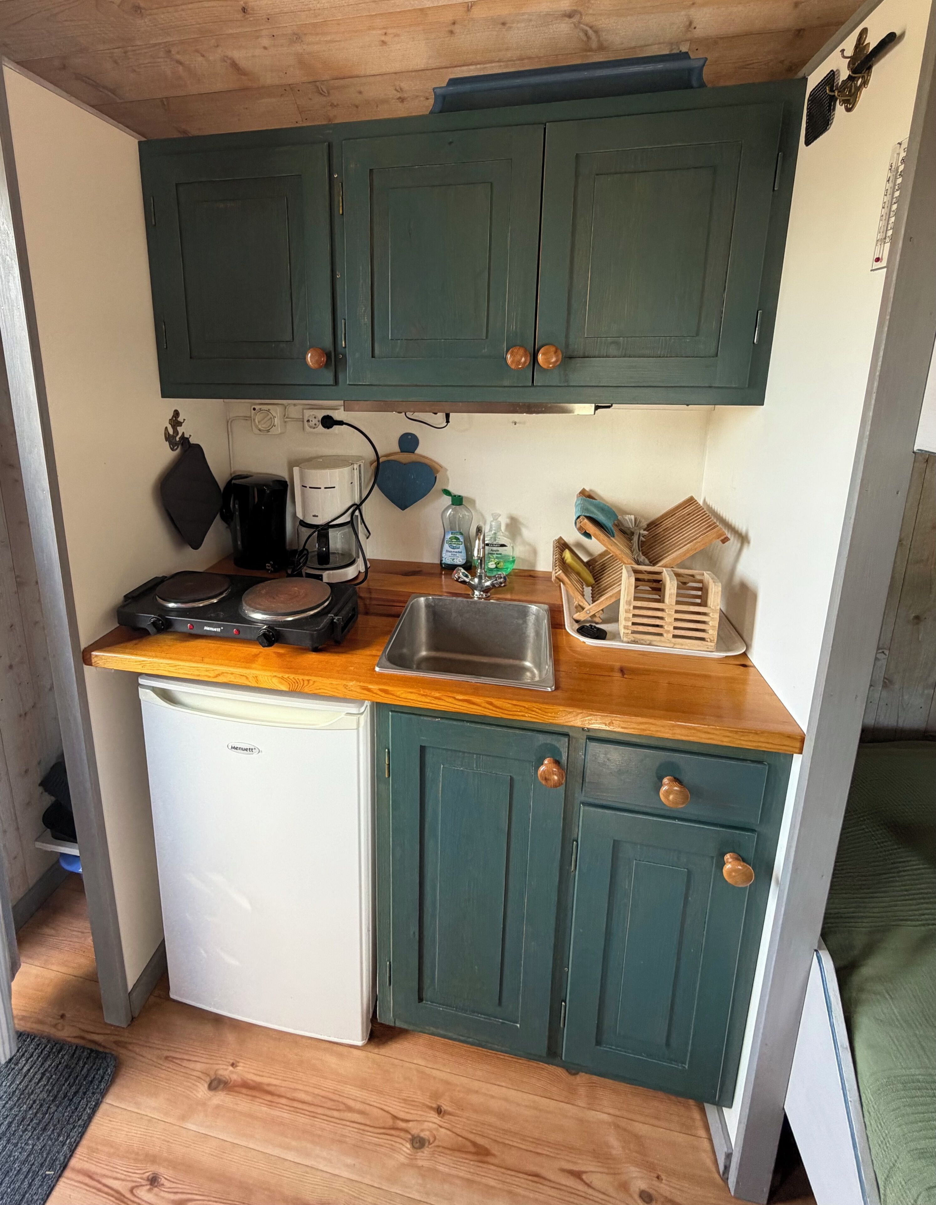 A compact kitchen with a white dishwasher, a coffee maker, and a sink.