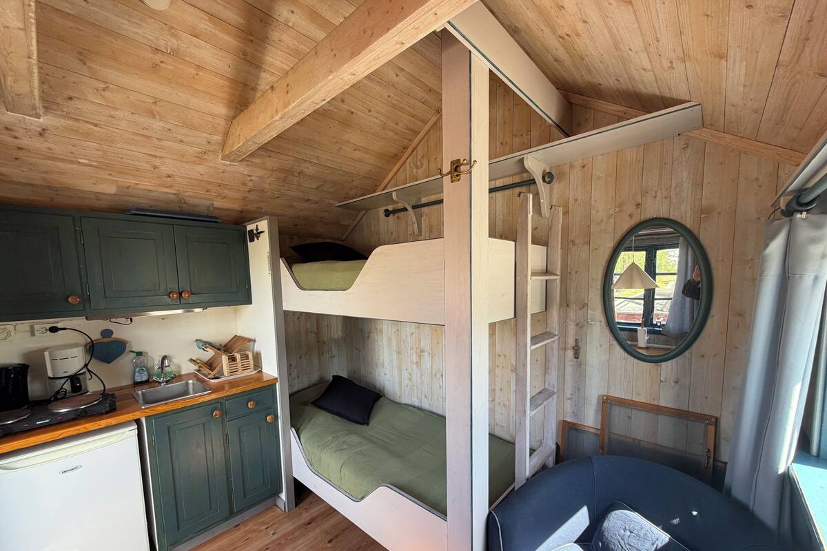 A compact cabin with a kitchenette, bunk beds, and a small seating area.