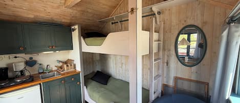 A compact cabin with a kitchenette, bunk beds, and a small seating area.