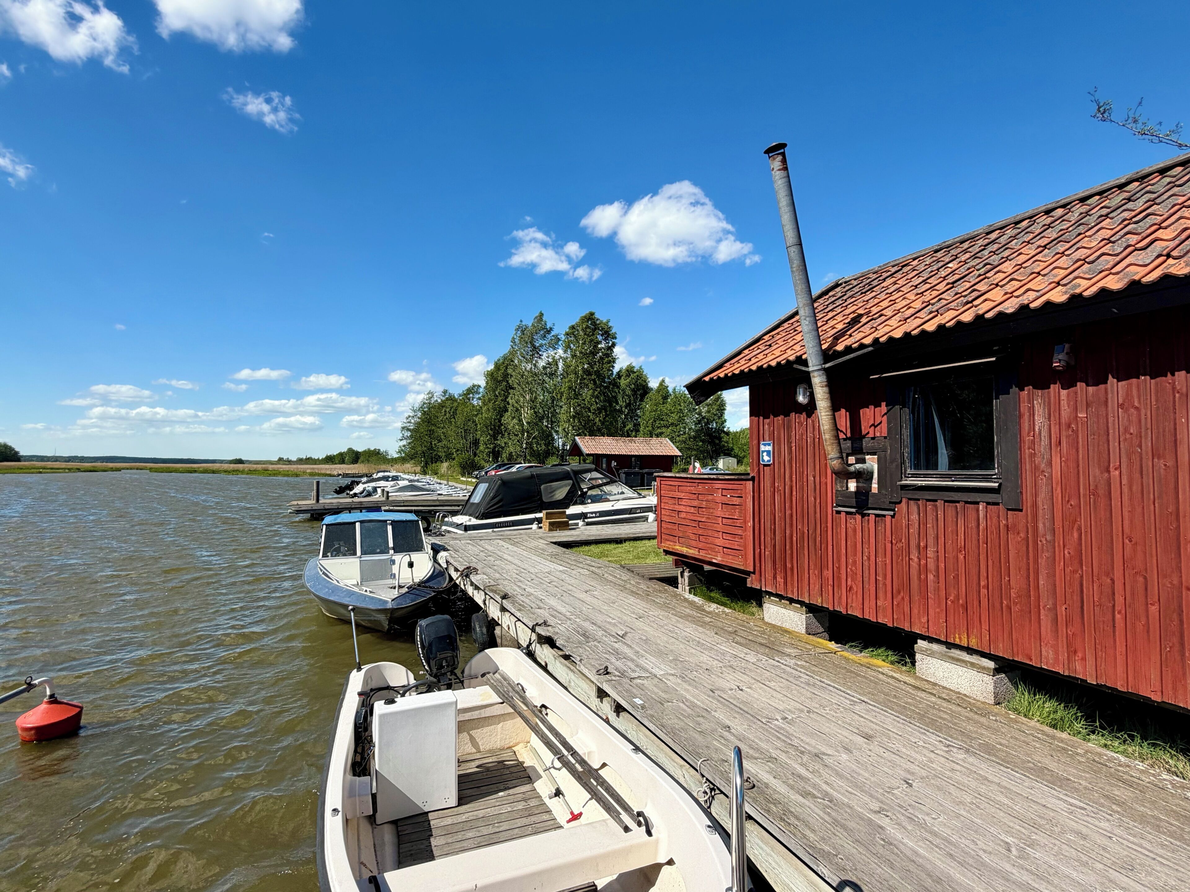 A dock with boats, a red wooden building, and a clear blue sky.