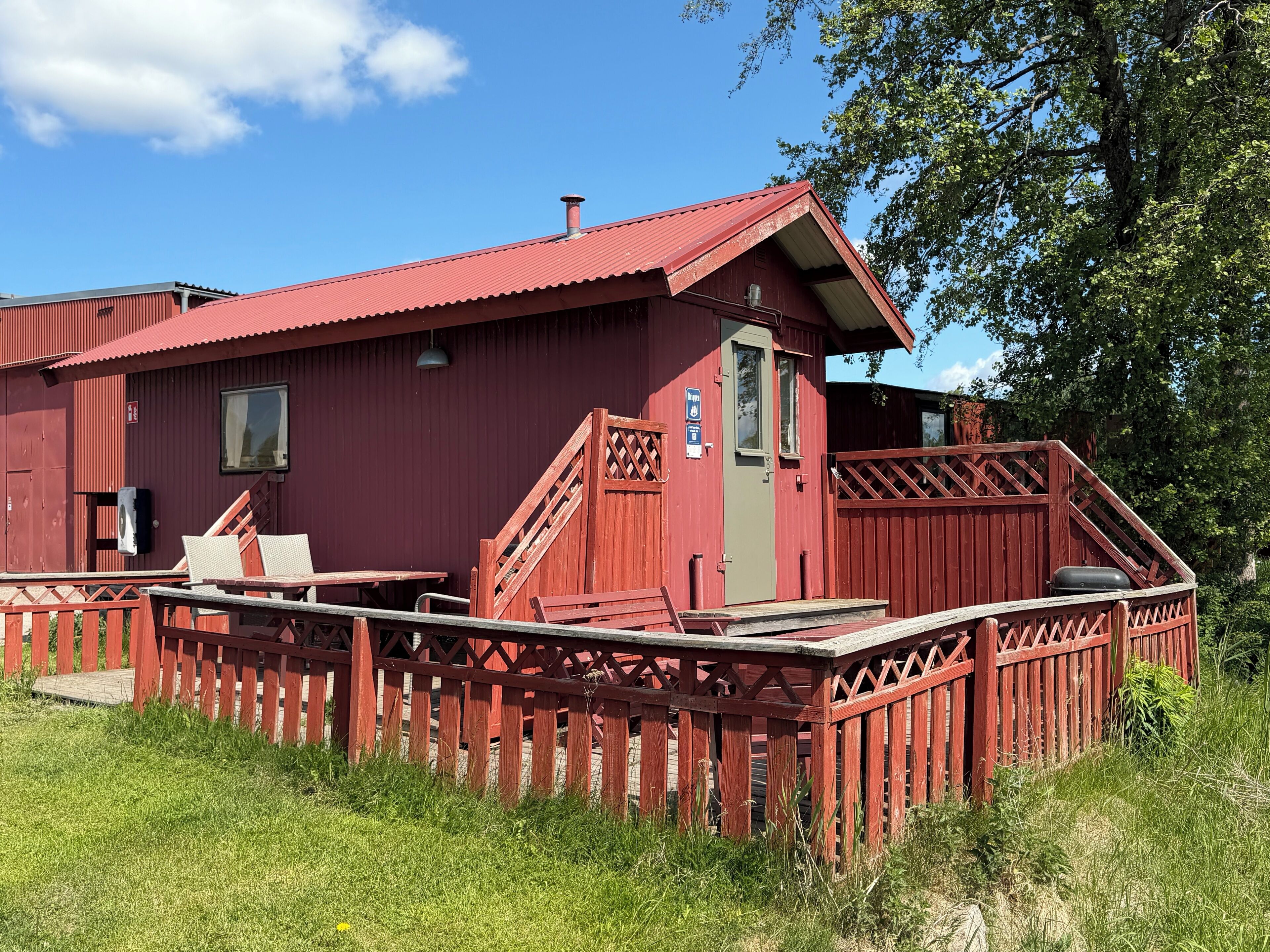 A red building with a wooden deck, a door, and a window.