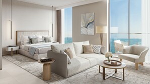 Una habitación de hotel moderna con cama, sofá, sillón y una mesa de centro redonda.