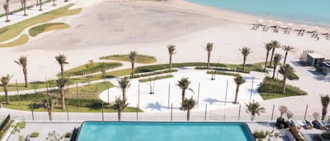 Un resort con piscina, playa y el horizonte de la ciudad al fondo.