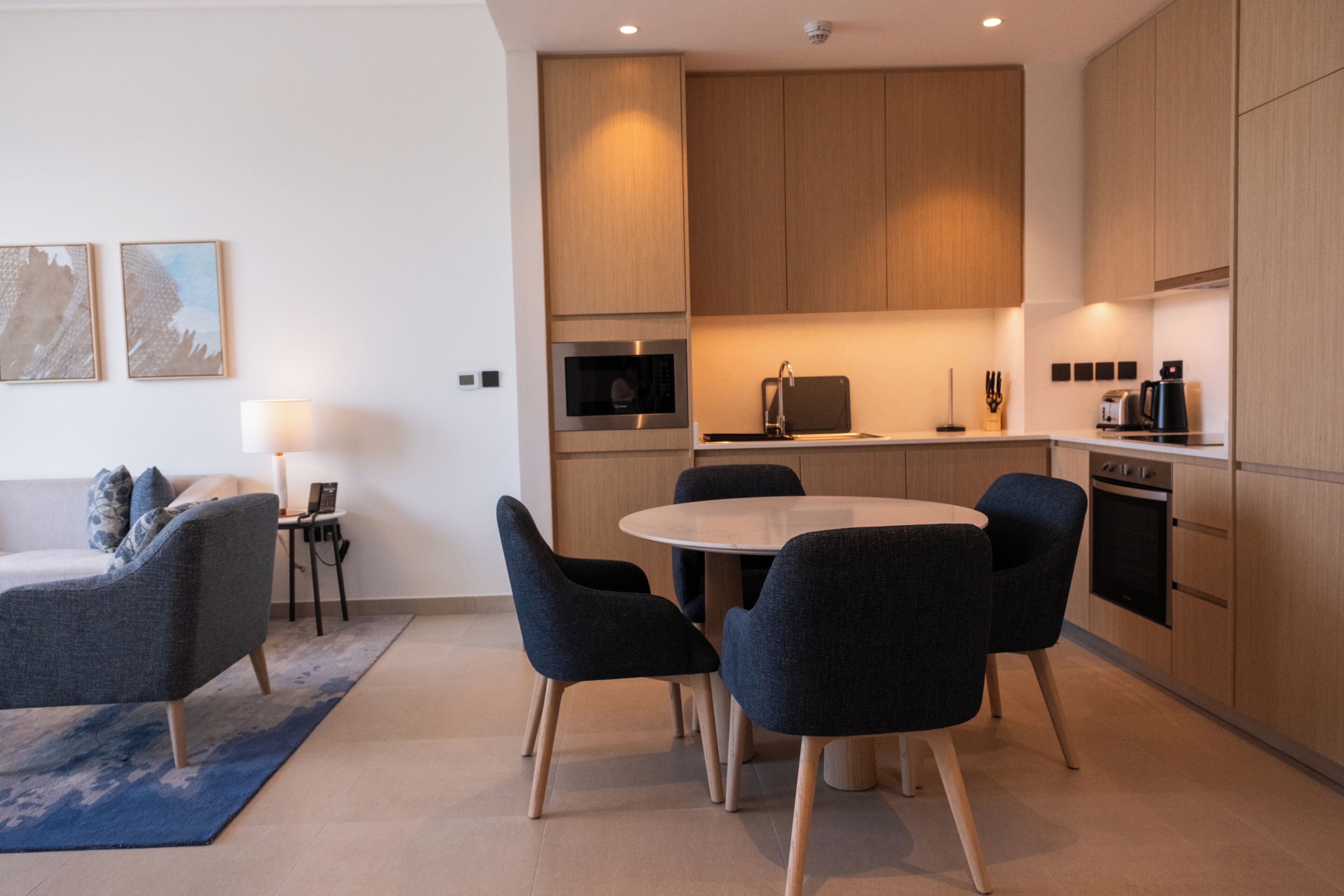 A modern kitchen with wooden cabinets, a round dining table, and four chairs.