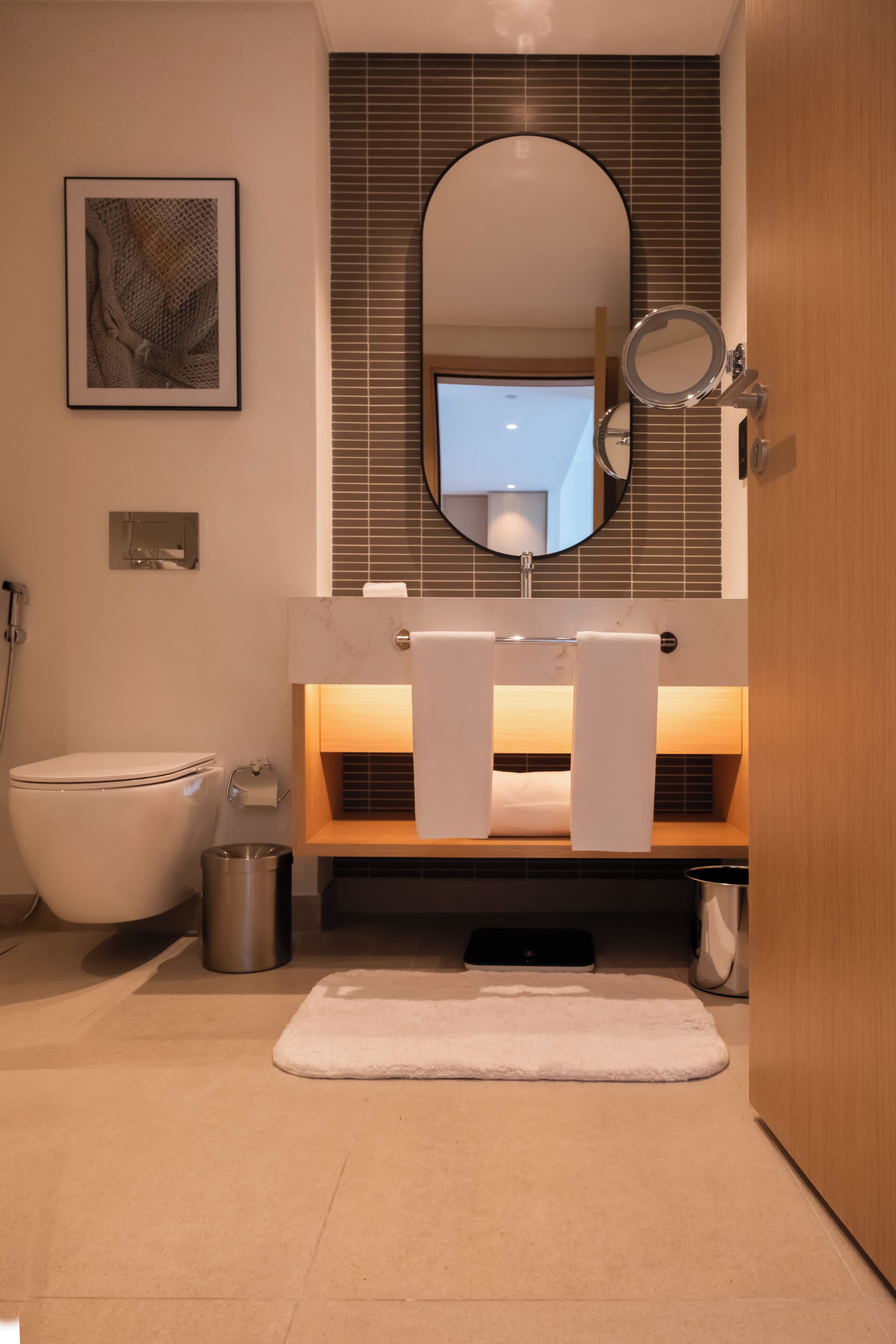 Un baño moderno con inodoro, bidé, lavamanos con espejo y un perchero para toallas.