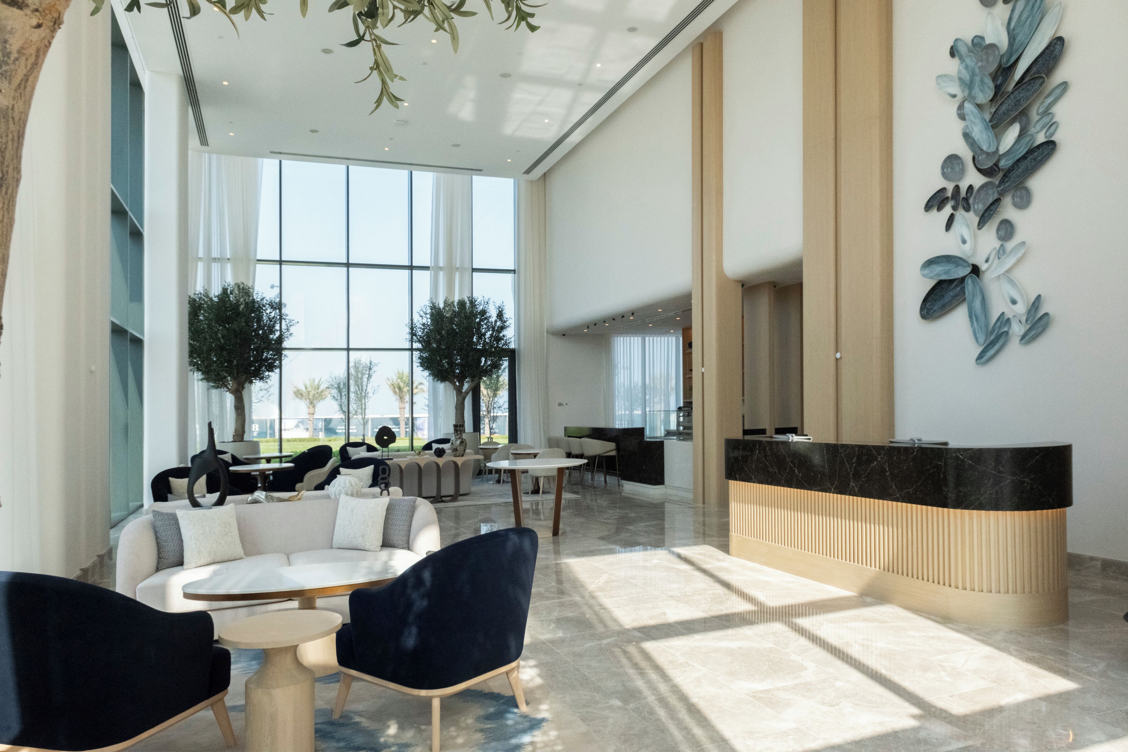 A spacious lobby with a reception desk, seating area, and large windows.
