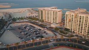 Un hotel de gran altura con varios pisos, estacionamiento y vista al mar.