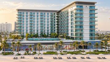 Ein modernes Hotel mit Pool, Strandliegen und Meerblick.