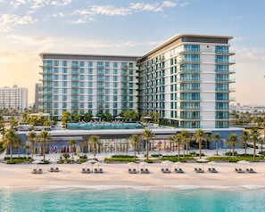 Un hotel moderno con piscina, zona de descanso en la playa y vistas al océano.