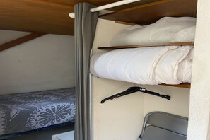 A bunk bed with a mattress on the upper bunk, a grey curtain, and a black hanger on the wall. - Bright apartment in Agde near the beach (Agde)