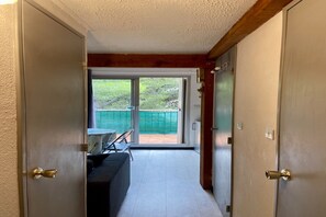 A corridor leading to a balcony with a view of greenery, a sofa, and a table. - Bright apartment in Agde near the beach (Agde)