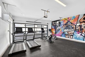 A gym with treadmills, a stationary bike, and a wall with exercise photos. - Copper Sky Townhome - Pool & Gym (Phoenix)