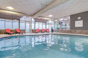 A swimming pool with red chairs, a clock, and a sign for Landmark Health & Fitness.