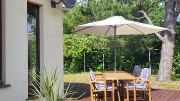 A wooden deck with a table and chairs, a satellite dish, and a large potted plant.