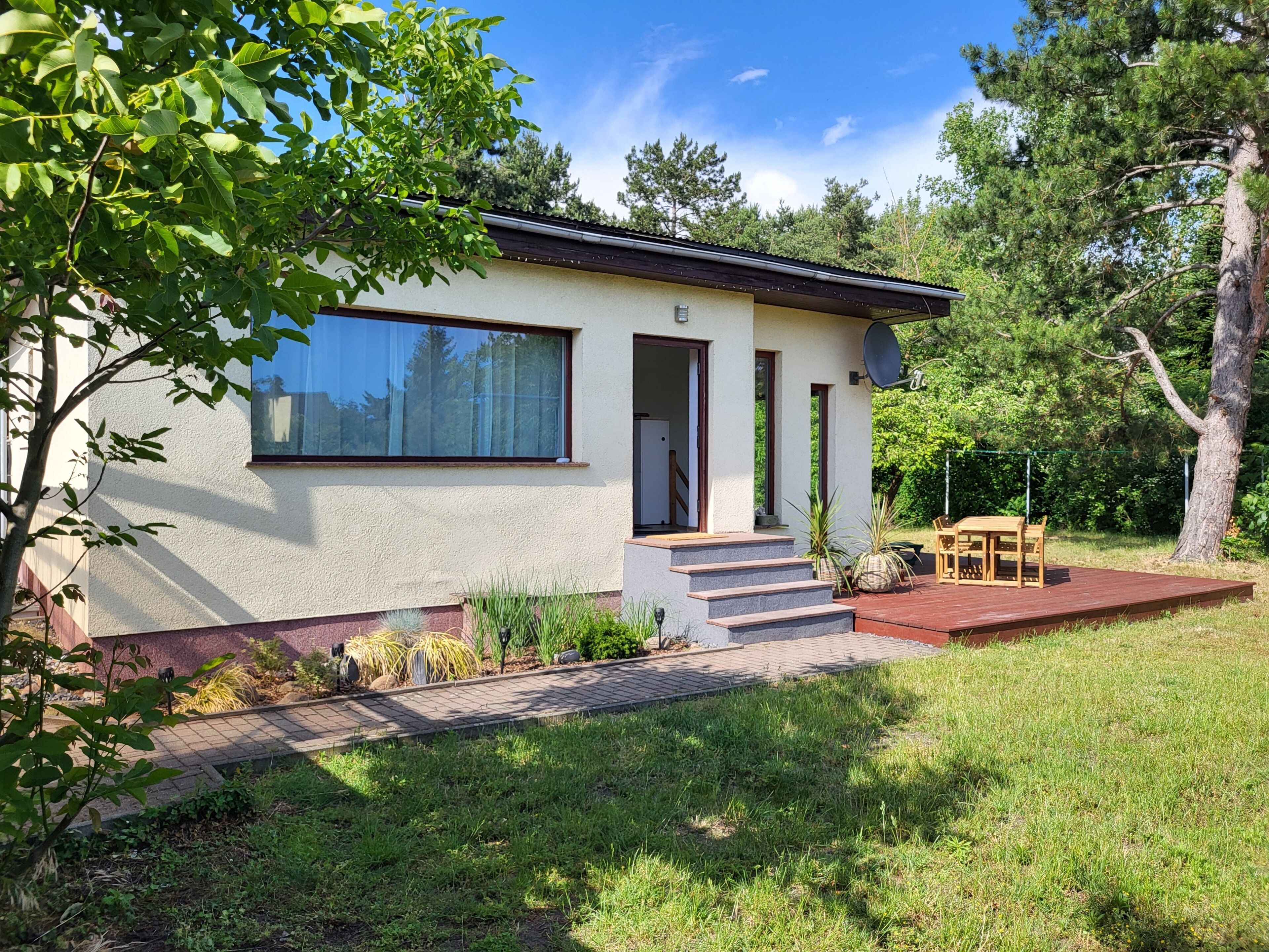 A modern house with a large window, a door, and a small outdoor seating area.