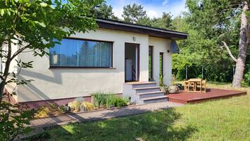 A modern house with a large window, a door, and a small outdoor seating area.