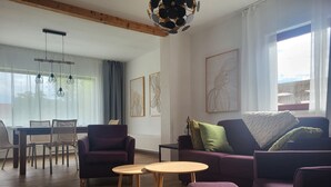 Olohuoneessa on puulattia, violetit huonekalut, pyöreä pöytä ja ruokailutila, jossa on tuoleja.