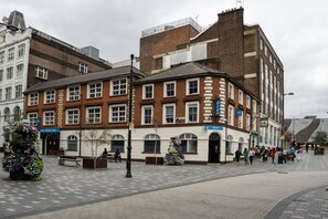 A public square with a historic building featuring multiple windows and a brick facade. - Small Double Room - No Window (Luton)