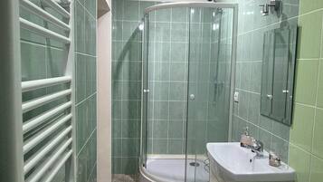 Un baño con ducha de vidrio, lavamanos y espejo.