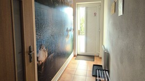 En hall med en väggmålning som föreställer ett berglandskap, en dörr med ett handtag, ett element och en bänk.