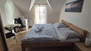 A bedroom with a bed, a desk, a chair, a radiator, and a window.