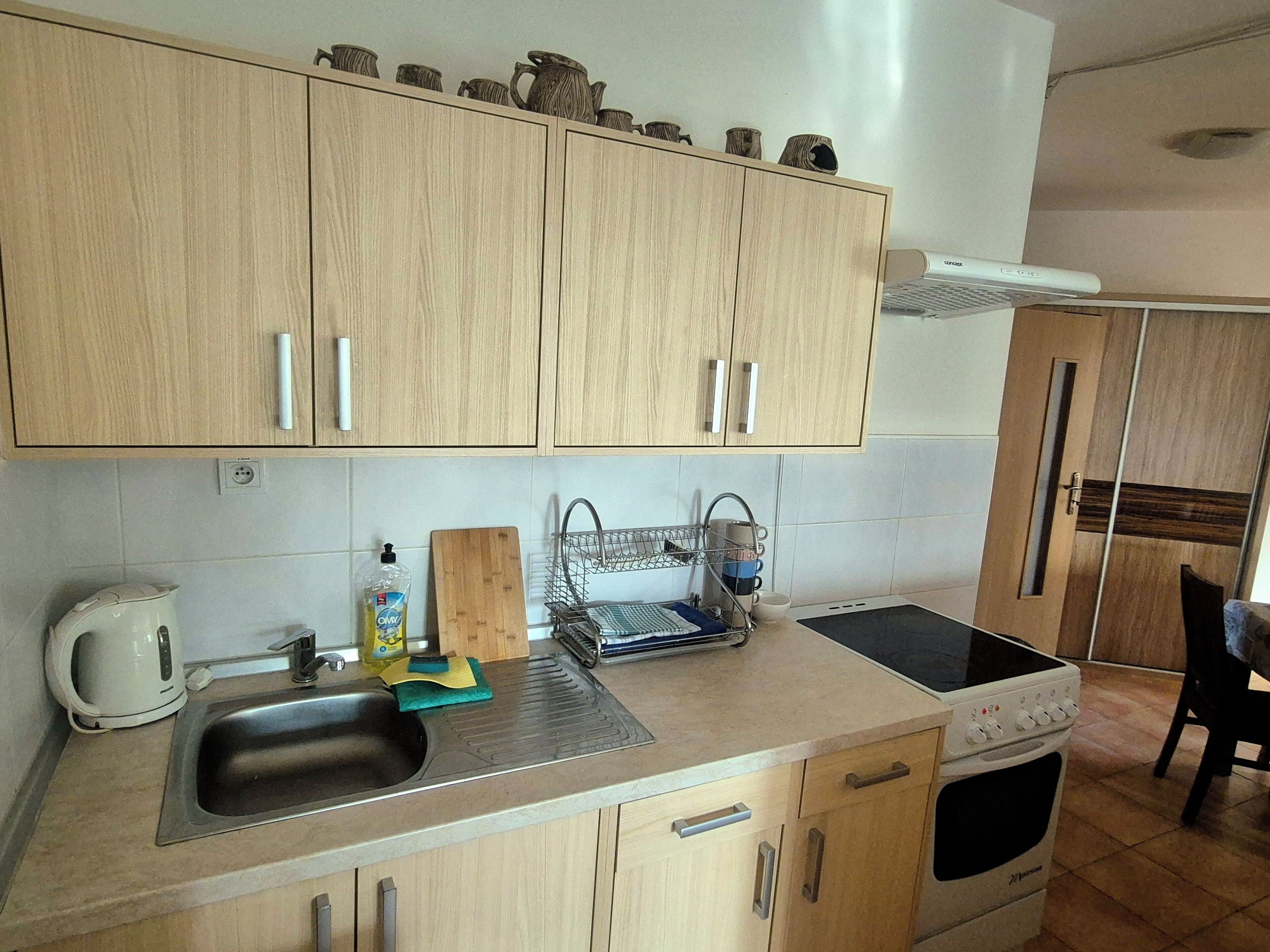 A kitchen with wooden cabinets, a sink, a stove, and a coffee maker.