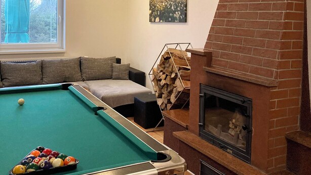 A room with a pool table, a fireplace, a sofa, and a painting on the wall.