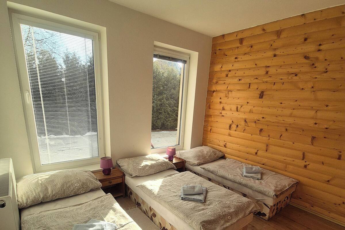 Habitación con tres camas, paredes de madera y una ventana.