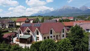 A house with solar panels, a covered patio, and a mountain backdrop.