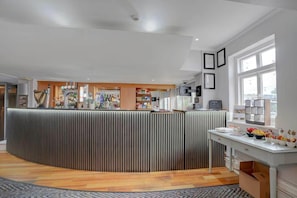 A modern bar area with a counter, shelves with bottles, and a window with a view.