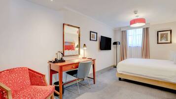 A hotel room with a bed, desk, chair, and a large mirror.